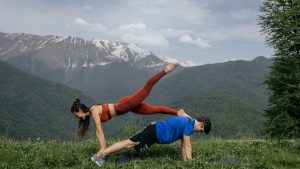 Couple doing yoga exercises outdoors with a breathtaking mountain view.